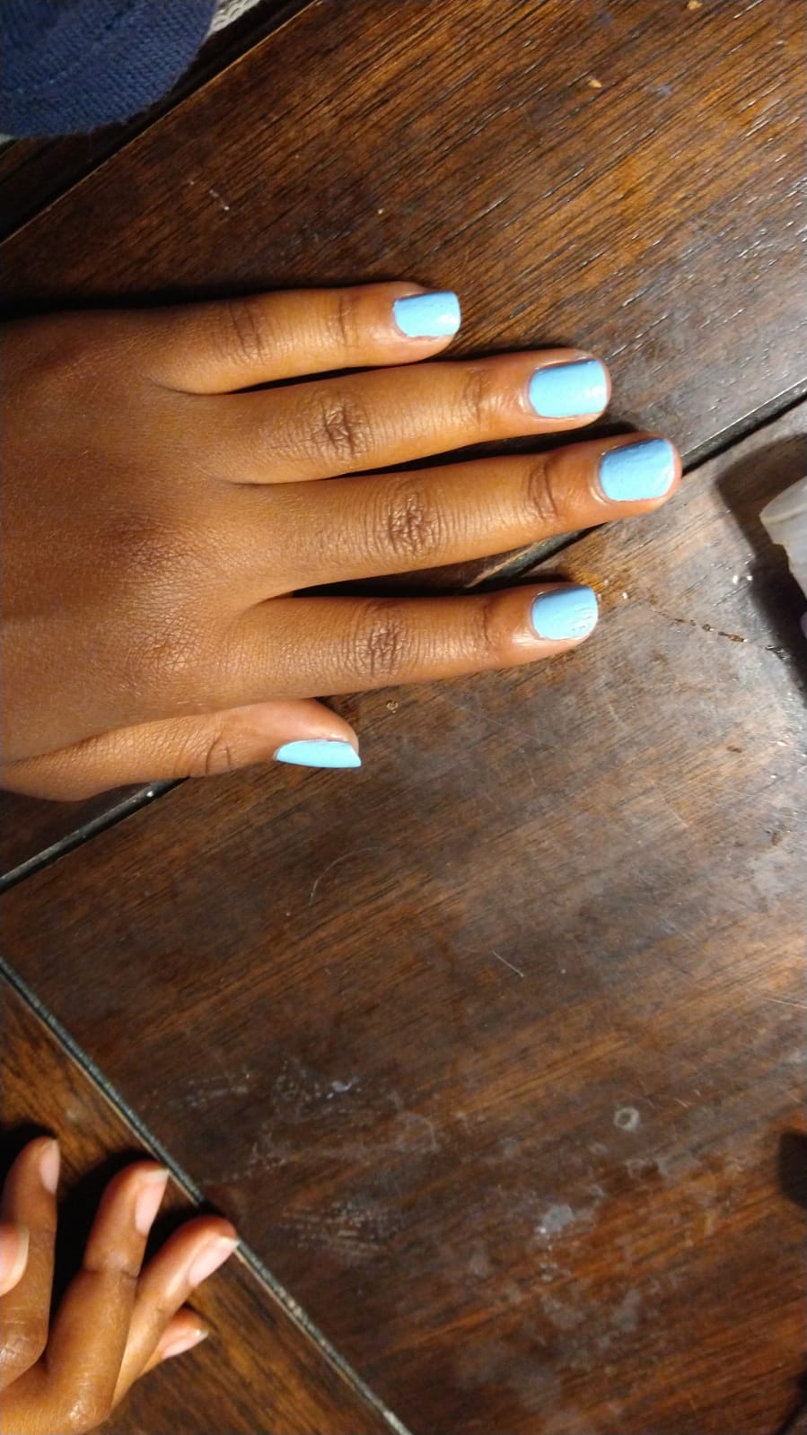 Fingernails painted bright sky blue